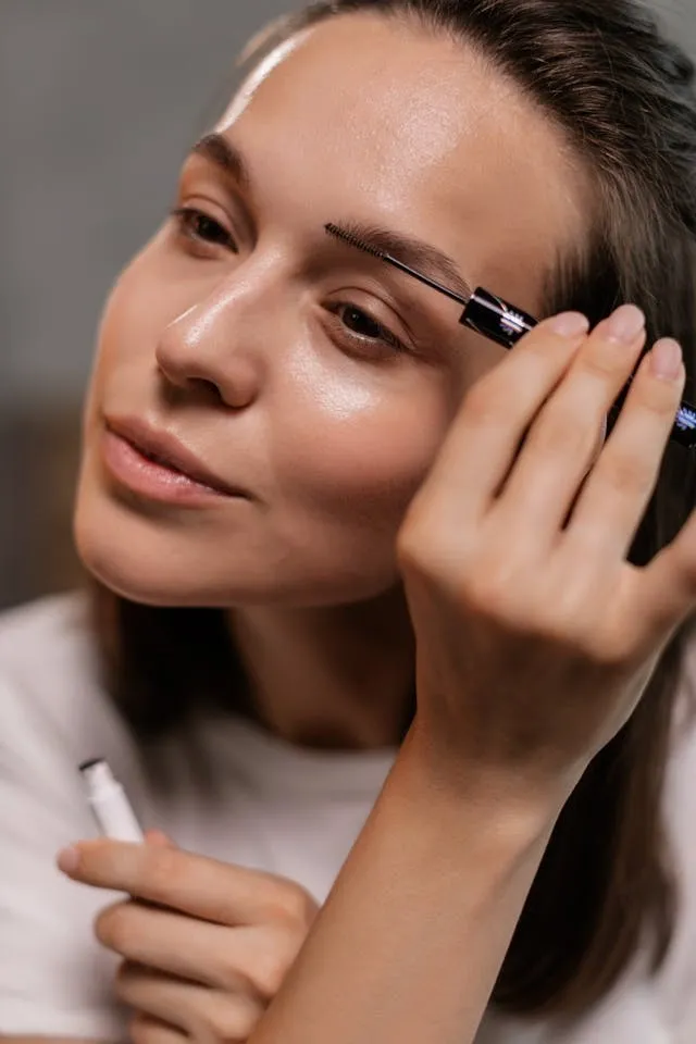 Routine maquillage sourcils avec gel fixateur transparent, mise en forme naturelle et lumineuse en gros plan sur peau nue.