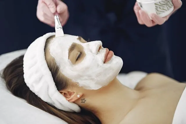 Femme recevant un masque visage blanc en institut, allongée avec bandeau confort
