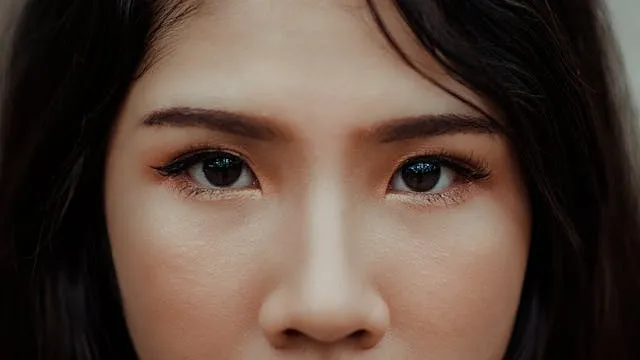  Regard intense d’une femme brune au visage centré, mise au point sur les yeux et les sourcils définis.