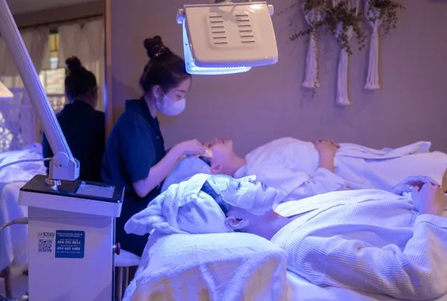 Soin du visage réalisé en cabine sous lumière LED bleutée, atmosphère professionnelle et relaxante en institut