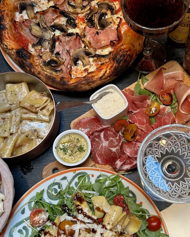 Festin italien authentique proposé par The Little Italy Shop – assortiment de pizza, pâtes, charcuterie et antipasti, ambiance conviviale, 2025.