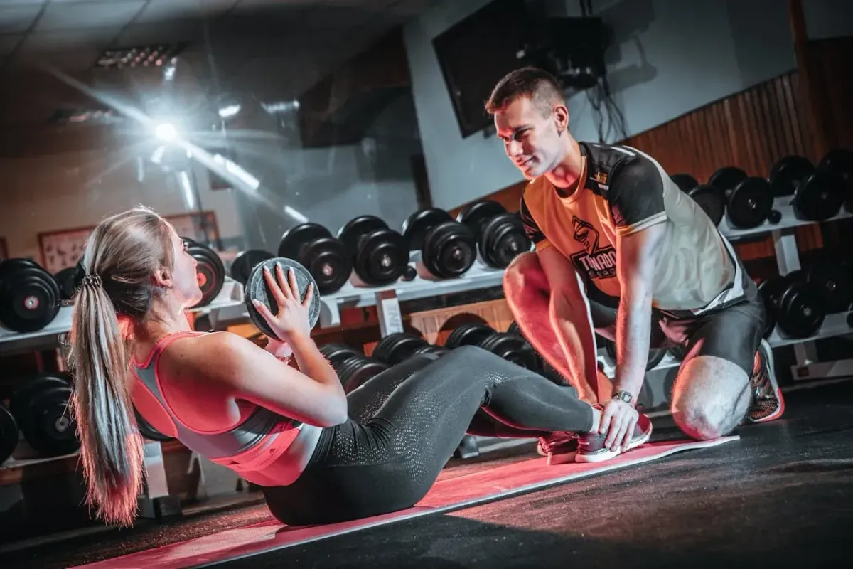 Coaching sportif en salle de musculation avec exercices abdominaux et haltères