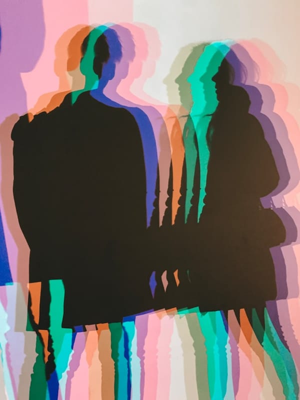 ombres colorées de silhouettes humaines projetées sur un mur, effet artistique kaléidoscopique