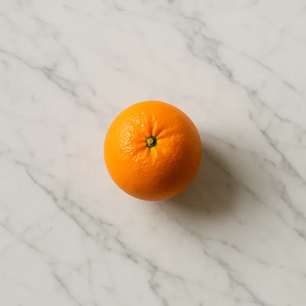 Orange posée sur un plan de travail en marbre clair veiné, composition minimaliste et naturelle en cuisine