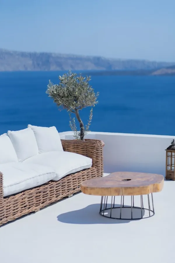 Terrasse contemporaine en bord de mer avec canapé en rotin, table basse en bois et vue dégagée sur la Méditerranée