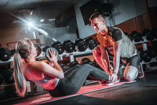 Coaching sportif en salle de musculation avec exercices abdominaux et haltères