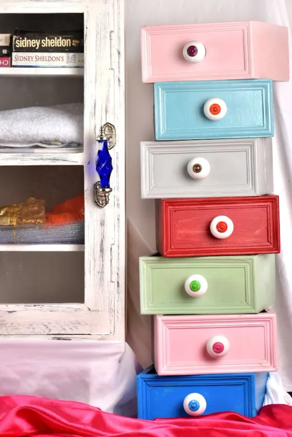 Commode colorée aux tiroirs déstructurés et vitrine blanche avec poignée bleue, style déco éclectique