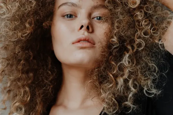 Portrait gros plan d’une femme aux cheveux bouclés naturels et à la peau lumineuse