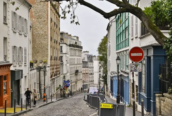 Rue pavée en pente de Montmartre à Paris, immeubles anciens, signalisation et ambiance typiquement parisienne